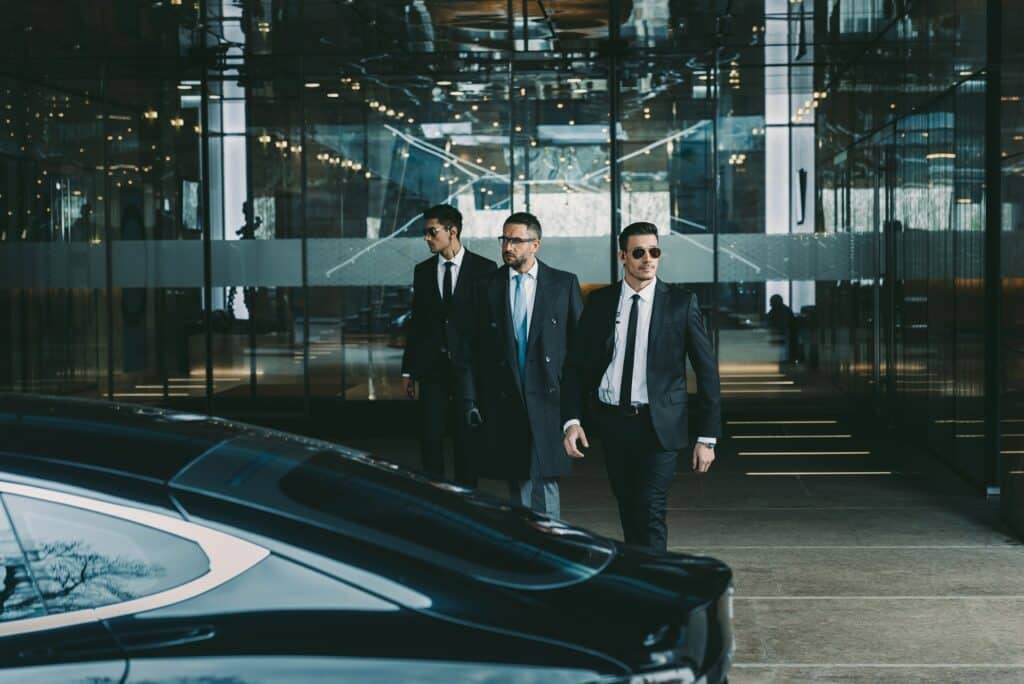 businessman and two bodyguards walking to car