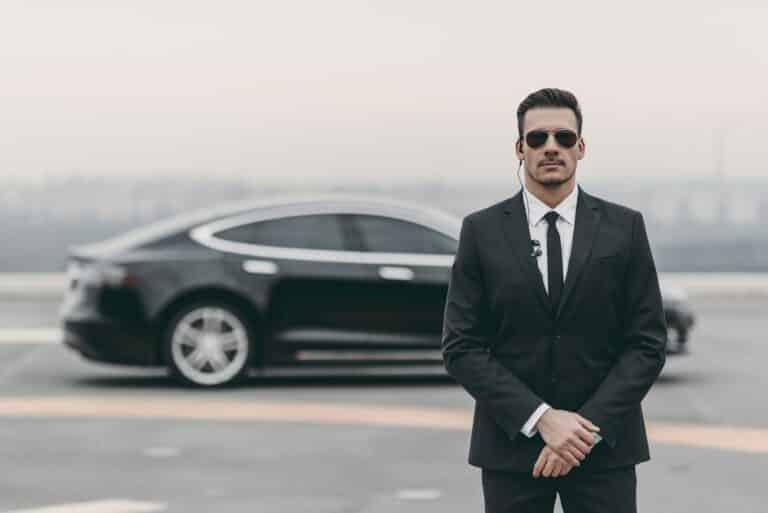 serious bodyguard standing with sunglasses and security earpiece on helipad